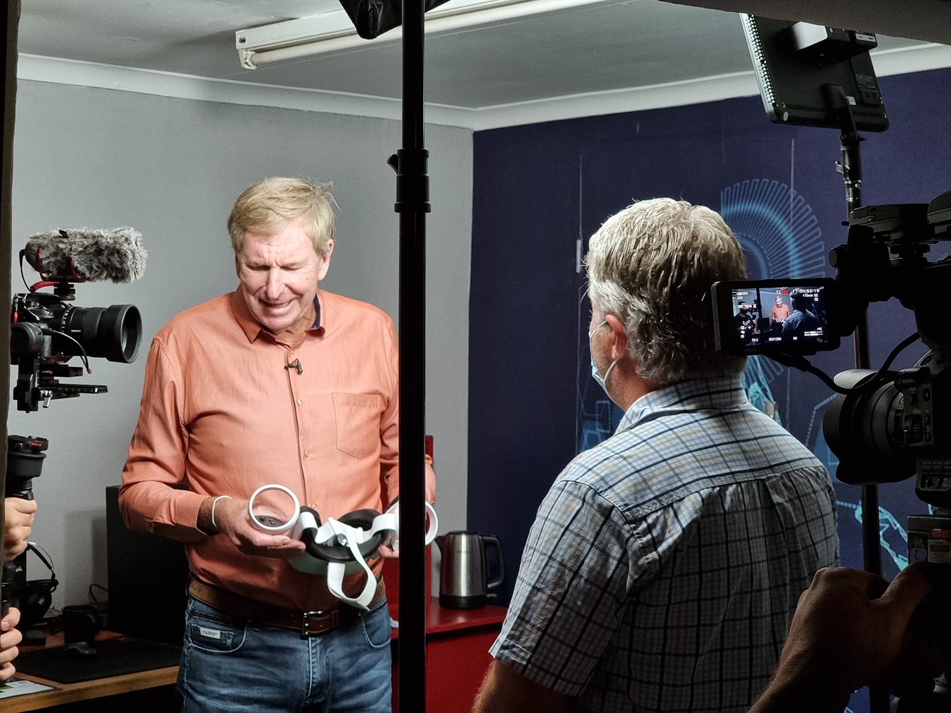 Derek Watts holding VR controllers during a filmed visit to Virtual Reality South Africa