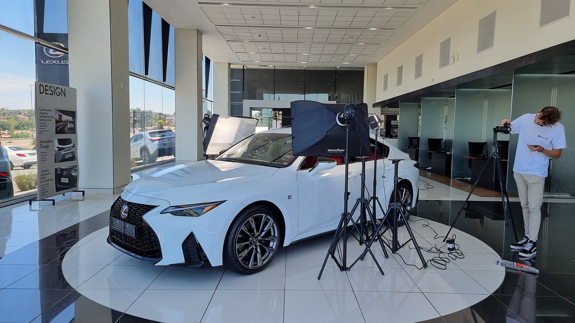 The Lexus IS300h being photographed with studio lights on a showroom floor