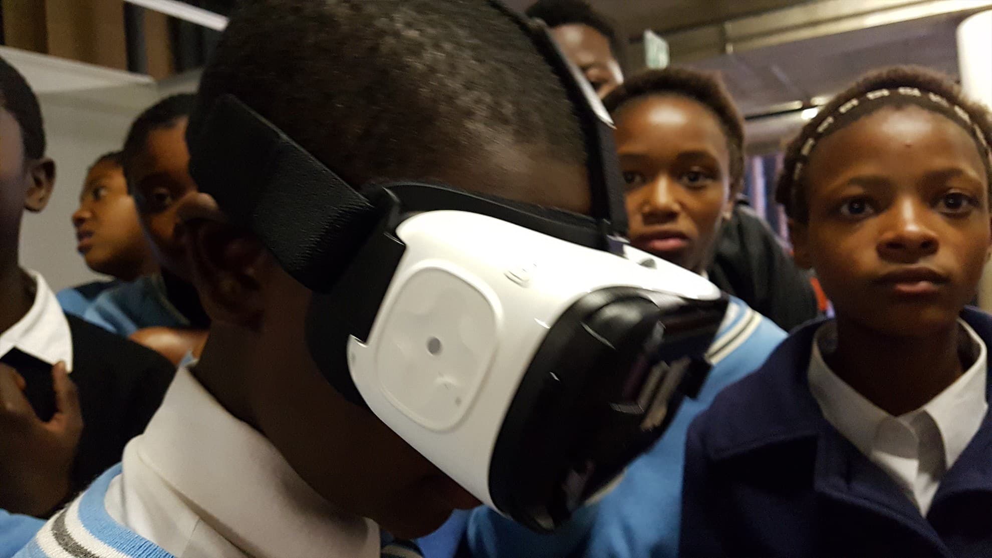 Participant wearing a white Gear VR headset as visitors watch